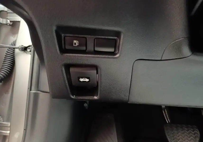 Détail des commandes d'ouverture de trappe à carburant et de capot côté conducteur d'un Lexus UX gris clair 2023.