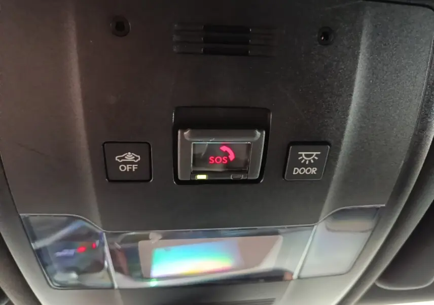 Vue rapprochée du panneau de commande intérieur au plafond du Lexus UX 250H gris clair, avec bouton SOS rouge central.