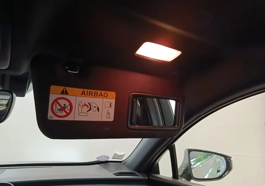 Intérieur du Lexus UX 250H 2WD gris clair, vue côté passager avec pare-soleil et miroir éclairé.