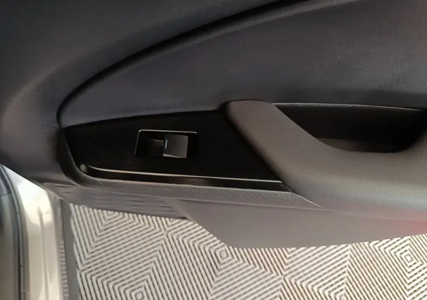Détail de la poignée intérieure et commande de lève-vitre côté conducteur d’un Lexus UX 250H gris clair.