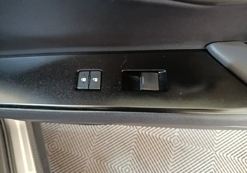 Gros plan sur les commandes de verrouillage des portes côté conducteur d’un Lexus UX 250H gris clair.