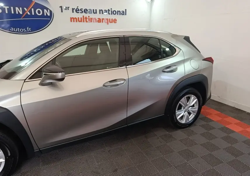 Profil côté gauche du Lexus UX 250H 2WD gris clair, avec jantes alliage et rétroviseurs assortis.