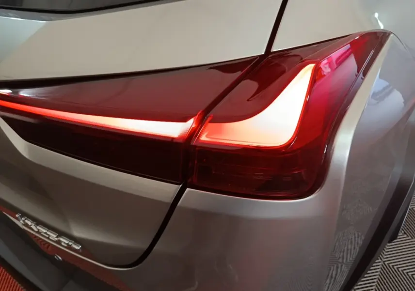 Gros plan sur le feu arrière droit rouge allumé d’un Lexus UX 250H gris clair, avec lignes LED distinctives.