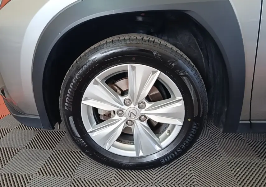 Gros plan sur la roue avant droite d'un Lexus UX 250H gris clair avec jante alliage et pneu Bridgestone.