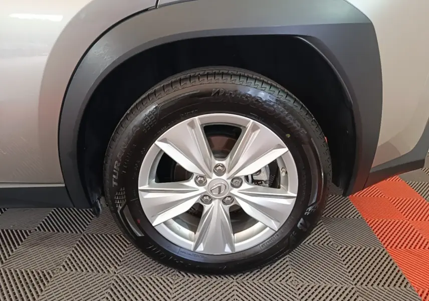 Gros plan sur la roue avant gauche gris clair du Lexus UX 250H 2WD Pack Business avec jante alliage et pneu Bridgestone.