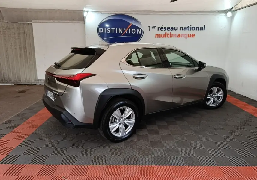 Lexus UX 250H gris clair en vue 3/4 arrière droit, avec feux arrière LED et jantes alliage visibles.