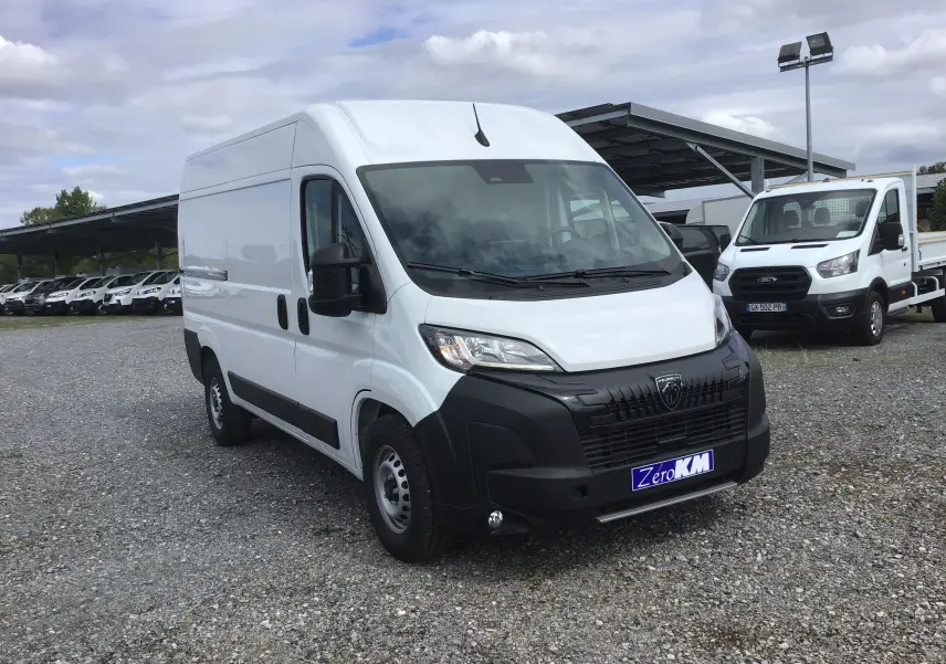 PEUGEOT Boxer Fourgon blanc en vue 3/4 avant droit sur parking avec calandre noire et plaque Zero KM.