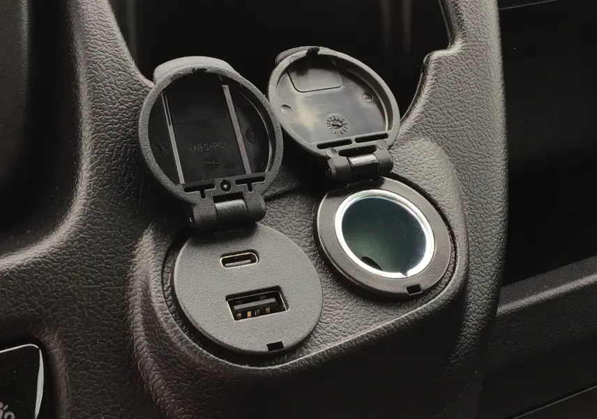 Prise USB-C et USB-A intégrée dans la console noire du Peugeot Boxer Fourgon blanc, version 2025, détail intérieur.