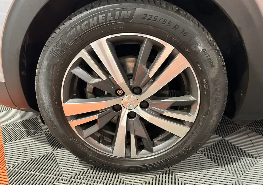Gros plan sur la jante alliage 18 pouces et pneu Michelin du Peugeot 3008 gris Artense, version Allure avec attelage.