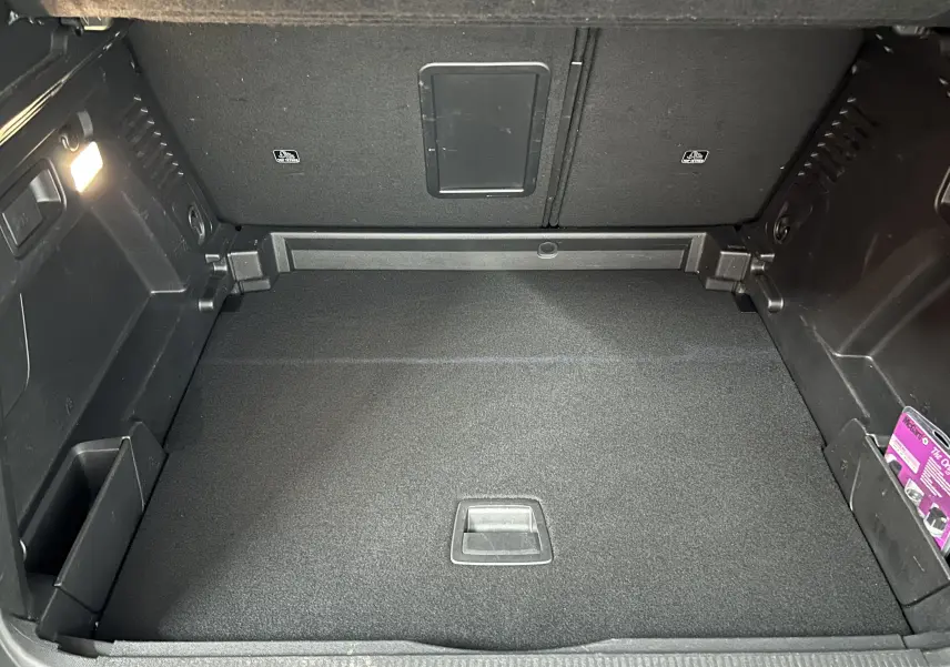 Vue intérieure du coffre spacieux et propre du Peugeot 3008 Puretech 130 Allure, avec revêtement noir et éclairage latéral.