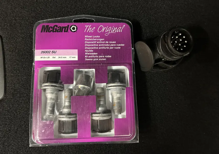 Je ne vois pas de véhicule sur cette image, uniquement un kit antivol de roues McGard et une prise électrique sur un fond noir.