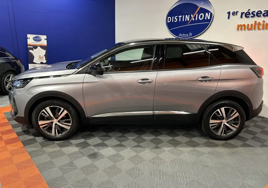 Profil droit d’un Peugeot 3008 gris Artense avec toit noir, en intérieur sur sol à motifs gris et orange, attelage visible.
