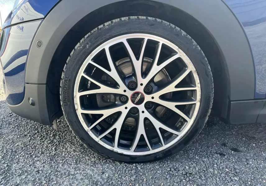 Gros plan sur la jante avant droite bicolore du MINI Cabriolet bleu, avec logo John Cooper Works au centre.