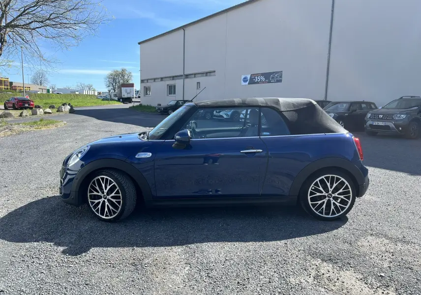 Vue latérale droite d'une MINI Cabriolet F57 Cooper S bleu avec capote noire fermée, roues alliage et détails noirs contrastants.