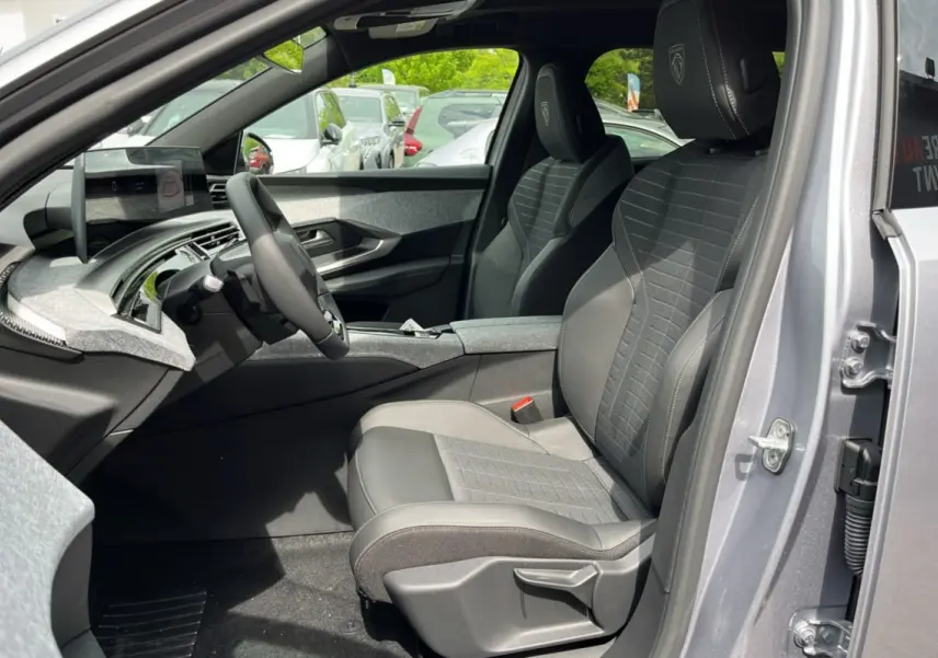 Vue intérieure côté conducteur du Peugeot 3008 New Hybrid 145 GT 360 avec sièges en tissu et cuir gris, volant multifonctions.