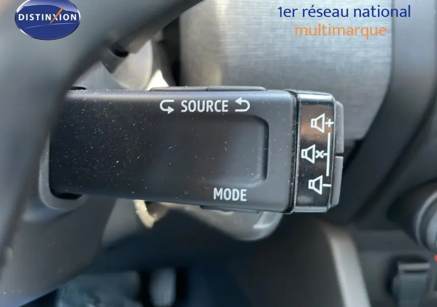 Gros plan sur la commande audio au volant d'une Renault Clio noire étoile métal, version BlueDCI 100ch Evolution 2025.