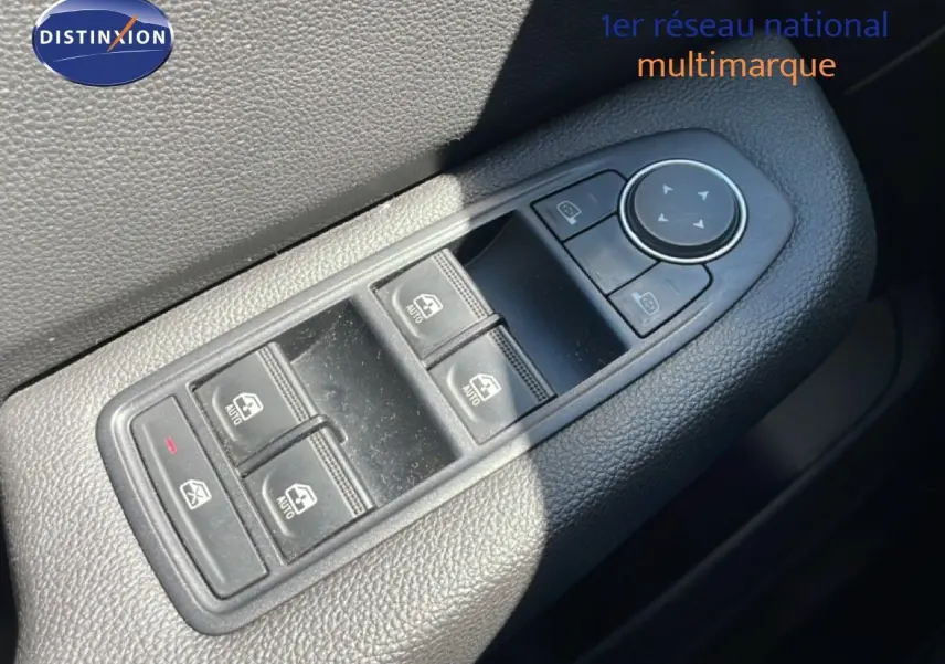 Gros plan sur les commandes de lève-vitres et rétroviseurs côté conducteur d'une Renault Clio noire étoile métal.