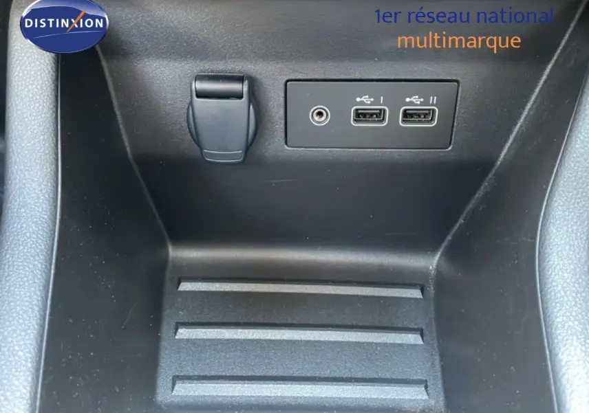 Gros plan sur la console centrale d'une Renault Clio noire, montrant deux ports USB et une prise jack.