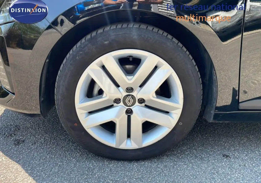Gros plan sur la roue avant gauche d'une Renault Clio noire étoile métal, mettant en valeur la jante argentée au design moderne.