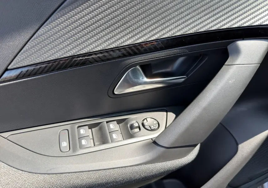 Gros plan sur la porte côté conducteur du Peugeot 2008 gris clair, montrant les commandes des vitres et le bouton de verrouillage.