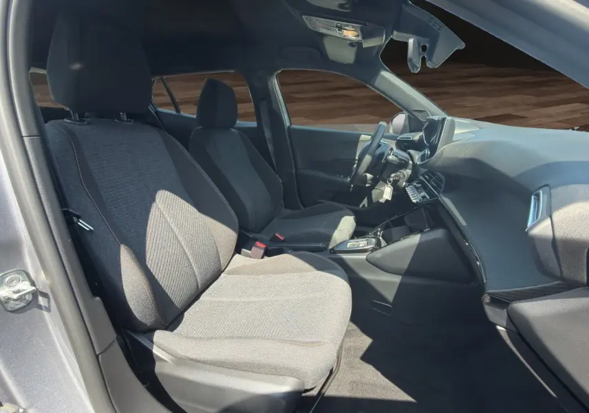 Vue intérieure côté conducteur du Peugeot 2008 Hybrid 145 e-DCS6 STYLE gris clair, avec sièges tissu et tableau de bord moderne.