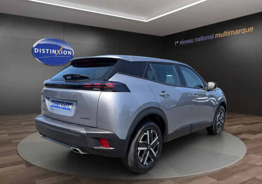Vue 3/4 arrière droite d'un Peugeot 2008 Hybrid gris clair avec feux arrière LED et jantes alliage bicolores.