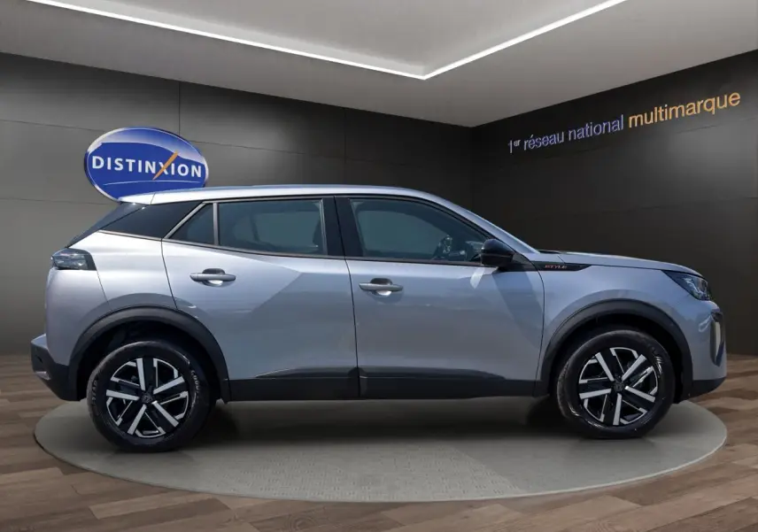Vue de profil côté gauche d’un Peugeot 2008 Hybrid 145 gris clair avec jantes noires et détails noirs contrastants.