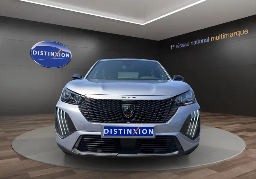 Vue frontale du Peugeot 2008 Hybrid gris clair avec calandre noire et feux LED verticaux allumés.