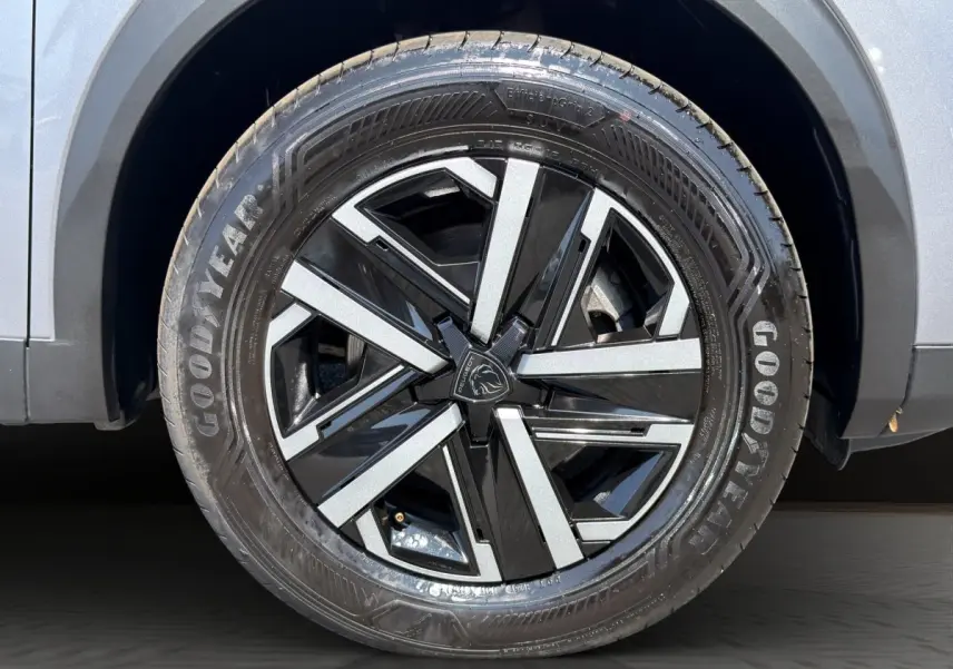 Gros plan sur la roue avant droite gris clair du Peugeot 2008 Hybrid 145 e-DCS6 STYLE avec jante noire et argent.