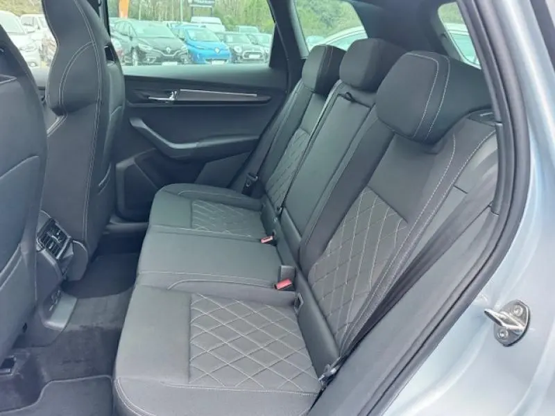 Vue intérieure côté droit des sièges arrière gris TEP/tissu du Skoda Karoq 2025 avec surpiqûres et appuie-têtes réglables.
