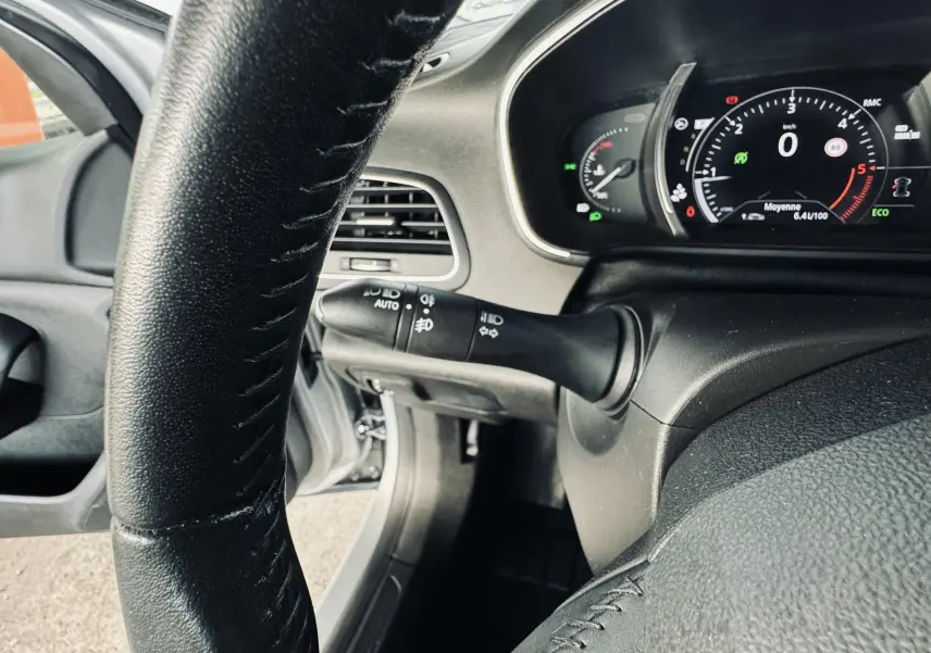 Vue rapprochée du tableau de bord et volant noir de la Renault Mégane IV Berline gris, affichage numérique au ralenti.