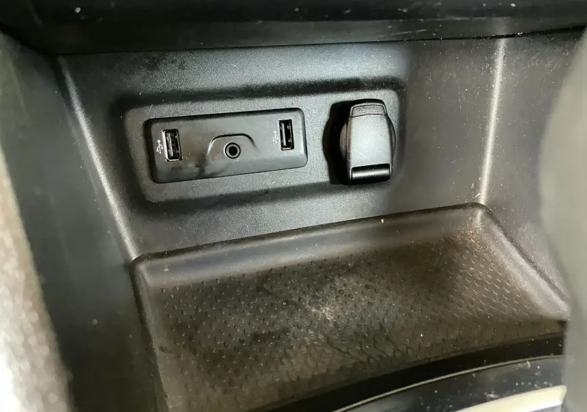 Gros plan sur la prise USB et prise allume-cigare dans l'habitacle noir d'une Renault Mégane IV Berline.