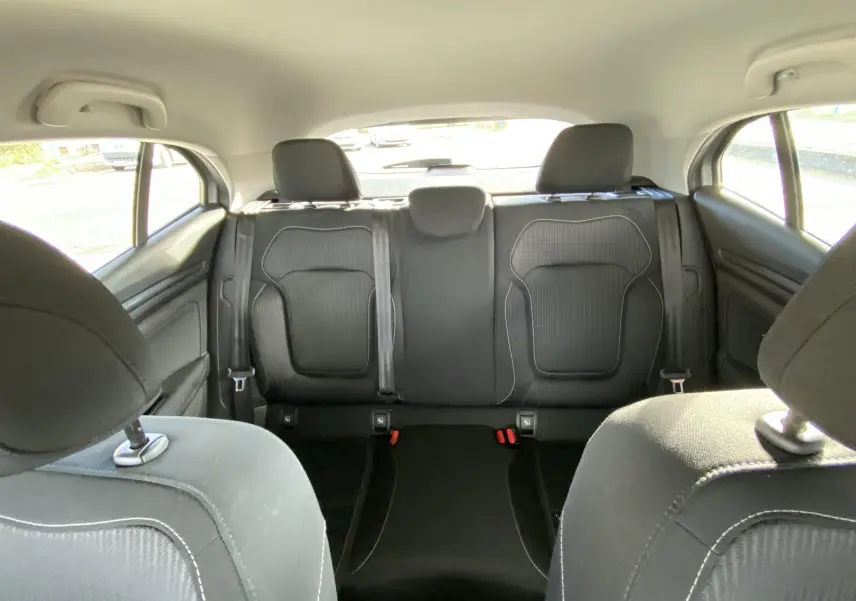 Vue intérieure arrière des sièges noirs en tissu de la Renault Mégane IV Berline gris, avec appuie-têtes et ceintures visibles.