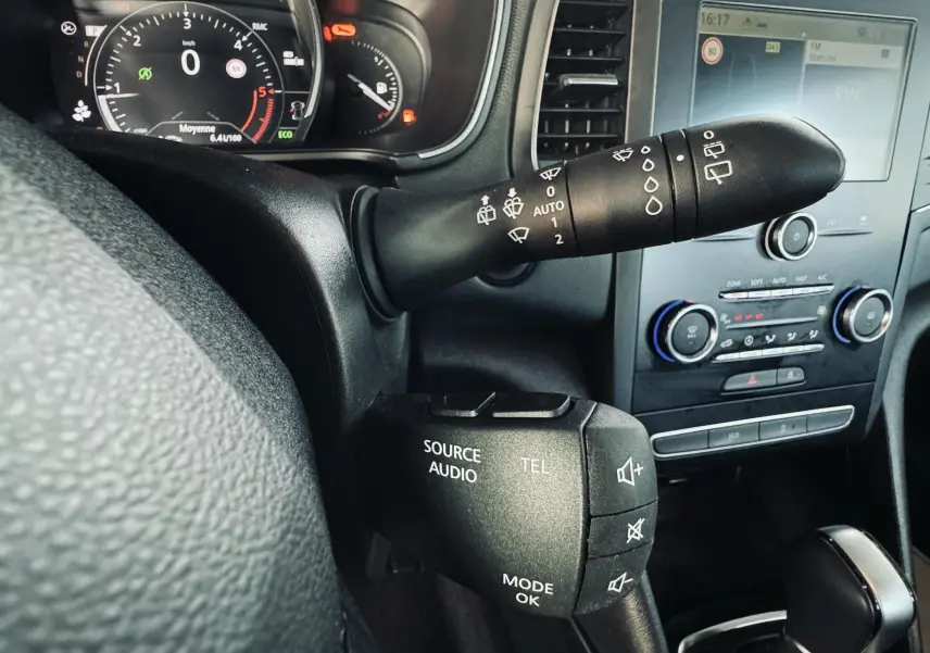 Gros plan sur le volant et la commande audio de la Renault Mégane IV Berline 1.5 Blue dCi 115ch Business, tableau de bord noir.