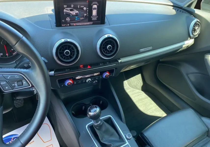 Vue intérieure côté conducteur de l'Audi A3 Sportback 2020, montrant la console centrale avec levier de vitesse manuel et écran multimédia.