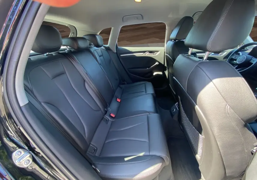 Vue intérieure arrière côté gauche d'une Audi A3 Sportback 2020 noire avec sellerie cuir noir chauffant et sièges sport.