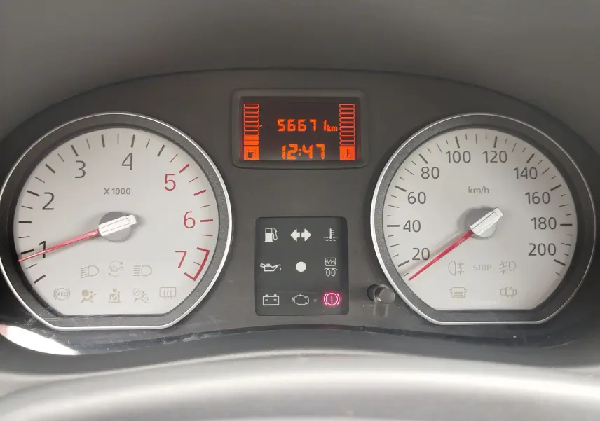 Tableau de bord de Dacia Sandero 2011, affichage digital orange avec compteur de vitesse et compte-tours blancs.