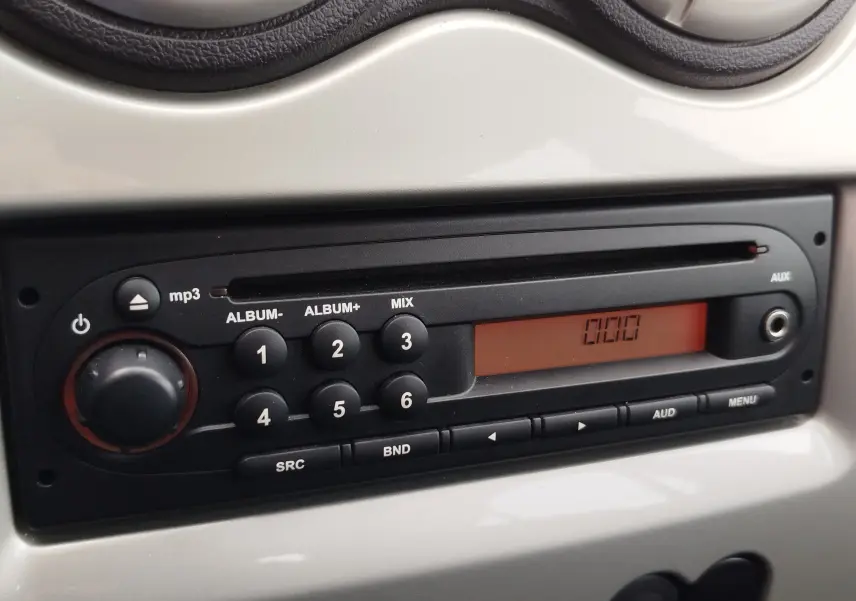 Gros plan sur la radio MP3 noire intégrée au tableau de bord gris clair de la Dacia Sandero 2011.