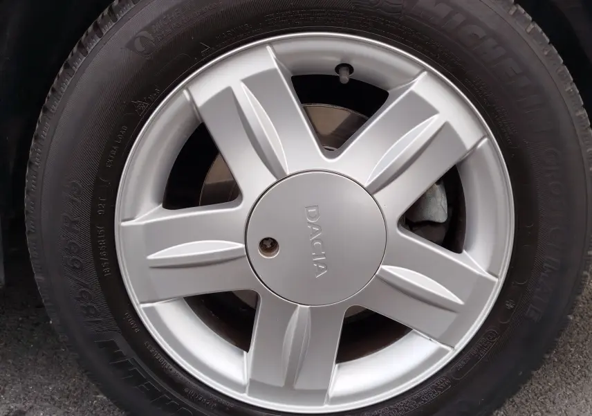 Gros plan sur la jante argentée de la DACIA Sandero noire, mettant en valeur le logo central et le pneu Michelin.