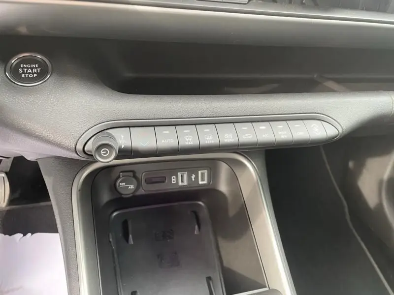 Vue rapprochée de la console centrale du Jeep Avenger gris métal 2025, avec boutons de climatisation et port USB visibles.