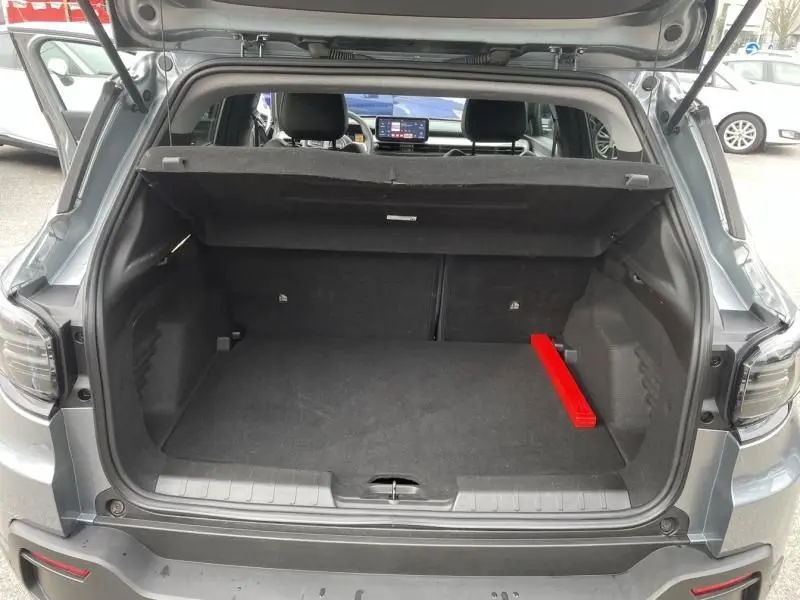 Coffre ouvert vu de l'arrière d'un Jeep Avenger gris métal 2025, avec un triangle de sécurité rouge visible à droite.
