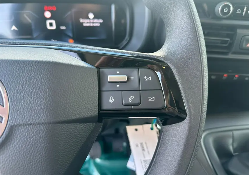 Vue intérieure arrière du Citroën Berlingo blanc Icy, porte latérale droite ouverte et cloison cabine partiellement rabattue.