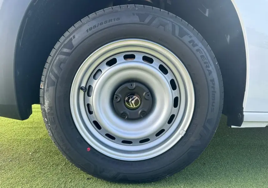 Gros plan sur la roue arrière droite en jante tôle grise du Citroën Berlingo blanc Icy, avec logo Citroën central.