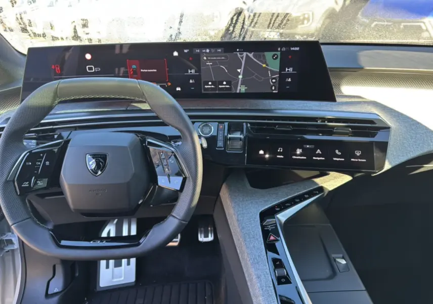 Vue intérieure du poste de conduite du Peugeot 3008 blanc okénite, avec volant cuir multifonctions et écran tactile panoramique.