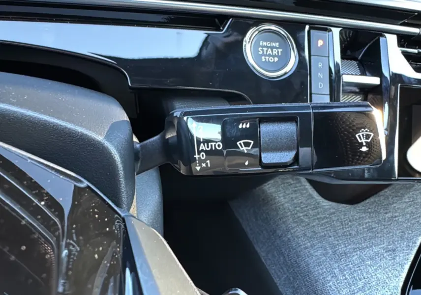 Gros plan sur la commande d'essuie-glace et le bouton start/stop du tableau de bord du Peugeot 3008 New Hybrid 2025.
