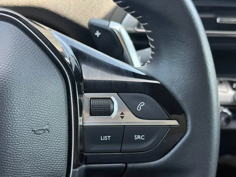 Gros plan sur les commandes multifonctions du volant cuir noir du Peugeot 3008 Hybride Rechargeable 2024, côté gauche.