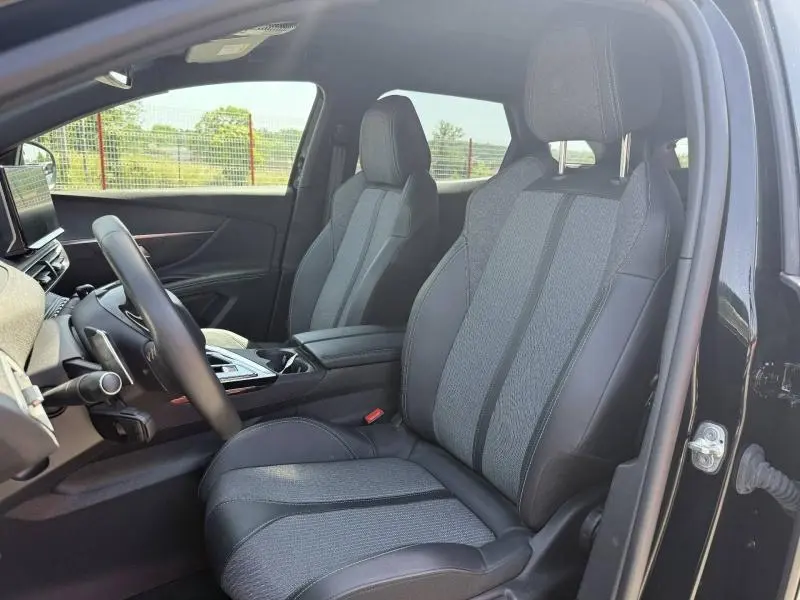 Vue intérieure côté conducteur du Peugeot 3008 Hybride Rechargeable 2024, sièges tissu et cuir gris, volant multifonction noir.