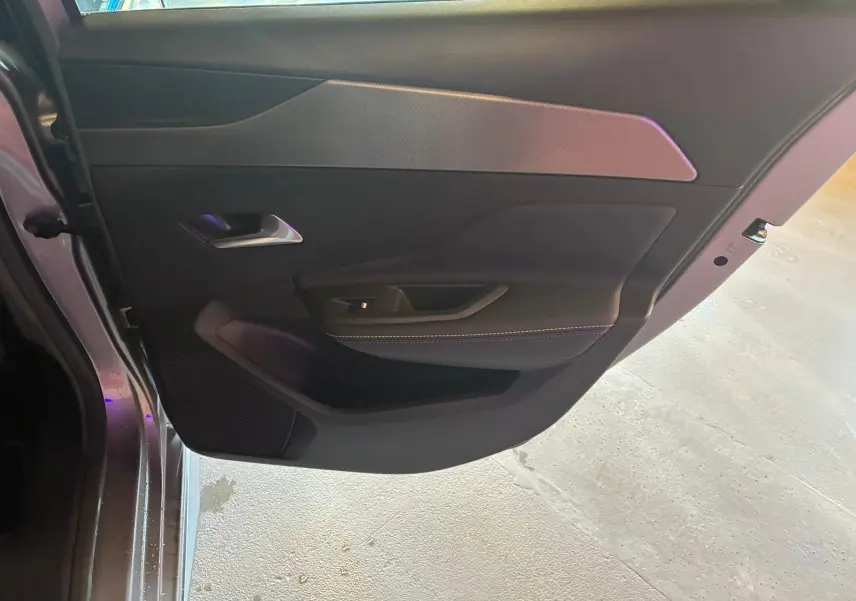 Vue intérieure de la porte arrière gauche gris foncé de la Peugeot 308 1.2 Hybrid 136 GT avec garniture textile et poignée argentée.