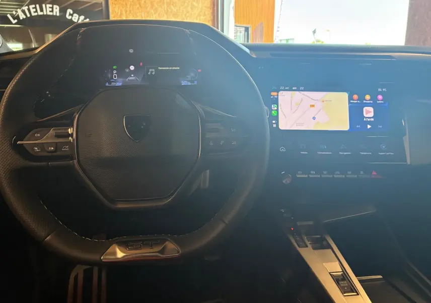 Vue intérieure centrée sur le volant noir de la Peugeot 308 GT avec écran tactile et affichage numérique lumineux.