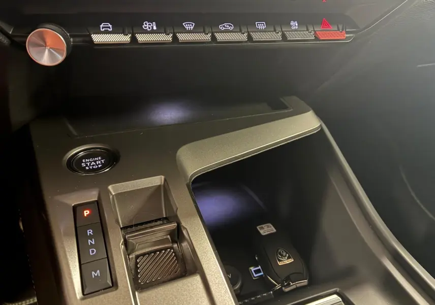 Vue rapprochée de la console centrale noire de la Peugeot 308 hybride 2025 avec sélecteur de vitesse et bouton start/stop.